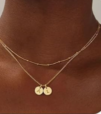 Una cadena fina en dorado o plateado con dos dijes circulares grabados con las iniciales que elijas. Simple y personal a la vez, para llevar algo tuyo o de alguien importante todos los días.